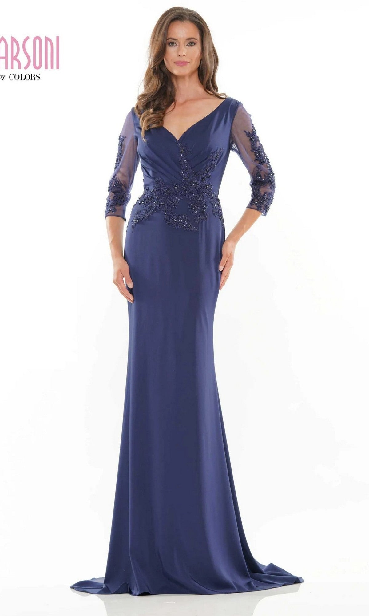 A woman stands against a white background wearing the Marsoni MV1145 long formal dress in navy, featuring sheer three-quarter sleeves and intricate beaded embellishments on the bodice.